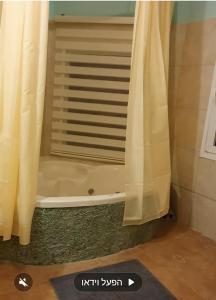 a bathroom with a bath tub with a shower curtain at Zman Midbar Eco Spirit Lodge for Peace in Arad