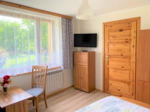 ein Schlafzimmer mit einem Tisch, einem Fenster und einer Holztür in der Unterkunft Agro-Jaga in Święta Katarzyna