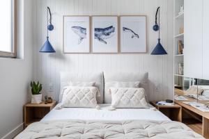 1 dormitorio con 1 cama blanca y 4 cuadros en la pared en Blue16 by OneApartments, en Gdansk