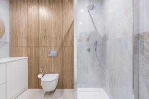 a bathroom with a white toilet and a shower at Blue16 by OneApartments in Gdańsk