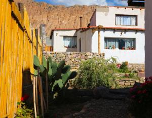 ein Haus mit einem gelben Zaun und einer Steinmauer in der Unterkunft Lo de Joaquin in Tilcara