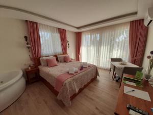 a bedroom with a bed and a tub and a table at Infinity Ruby Hotel in Fethiye
