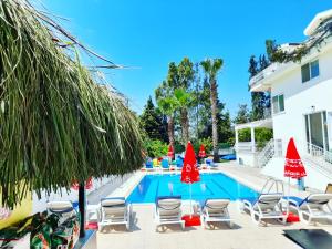 a swimming pool with chairs and umbrellas next to a house at Infinity Ruby Hotel in Fethiye