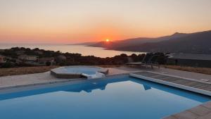 a swimming pool with a sunset in the background at Maison vue mer Propriano Viggianello in Viggianello