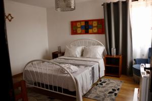 1 dormitorio con cama blanca y ventana en Casa Teresinha, en Sesimbra