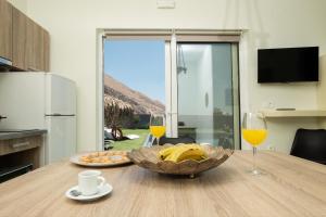 una mesa con un tazón de plátanos y dos vasos de zumo de naranja en Sagma Villas en Perissa