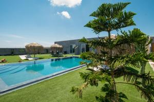 un'immagine di una piscina con una palma in primo piano di Sagma Villas a Perissa