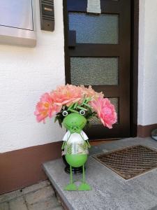 Un jarrón verde con flores rosas al lado de una puerta en Haus Akelei, en Todtmoos