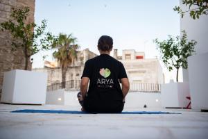 a man sitting on the floor looking out over a city at Arya Nobile Dimora in Carovigno