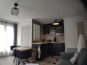 una cocina con armarios negros y una mesa en una habitación en Le COCON CABOURGEAIS en Cabourg