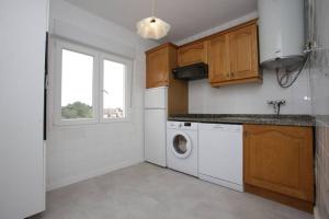 a kitchen with a washing machine and a window at Apartamento frente a la playa con vistas al mar en Barro, Llanes in Barro de Llanes