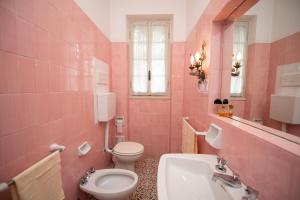 różowa łazienka z toaletą i umywalką w obiekcie Villa Sofia w mieście San Felice del Benaco