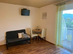 sala de estar con mesa, sillas y TV en Privatzimmer Haus Waltraud am Turnersee, en Obersammelsdorf