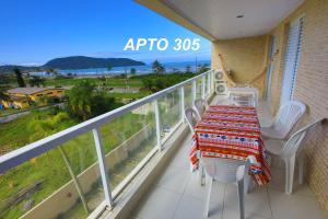 a balcony with a table and chairs and a view of the ocean at LINDO NOVISSIMO e PÉ NA AREIA in Bertioga