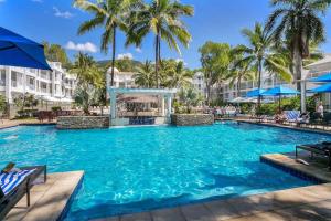 - une grande piscine dans un complexe avec des palmiers dans l'établissement Beach Club Palm Cove 2 Bedroom Luxury Penthouse, à Palm Cove