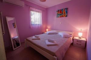 a bedroom with purple walls and a bed with towels on it at Cleopatra rooms in Nikiana +24 photos