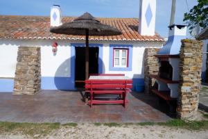 uma casa azul e branca com uma mesa e um guarda-chuva em Quinta do Sardanito de Tras na Zambujeira do Mar