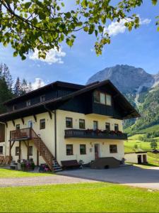 a large building with a staircase in front of a mountain at Reithgut in Sankt Martin am Tennengebirge