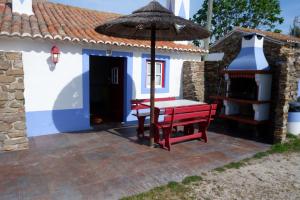 a patio with a table and an umbrella and a building at Quinta do Sardanito de Tras in Zambujeira do Mar