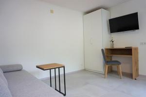 a room with a bed and a desk and a television at Zum Schwarzen Kus in Caldaro