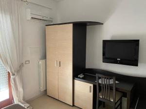 a room with a desk with a television and a cabinet at Città Bianca Country Resort in Ostuni