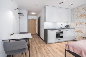 a kitchen with white cabinets and a table and chairs at Apartament Premium Kasprowicza 20A in Kołobrzeg