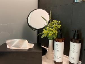 two bottles of soap and flowers on a table with a mirror at LÖFFELMÜHLE BOUTIQUE BED AND BREAKFAST in Pillig