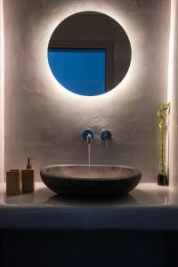 a sink in a bathroom with a round mirror at Blu Rooms in Akrotiri