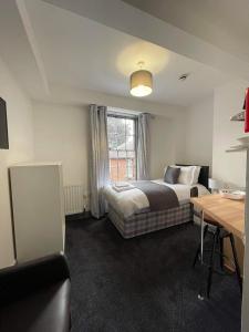 a bedroom with a bed and a desk and a window at Ty'r Bont Studios in Newtown