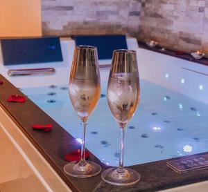 two wine glasses sitting on a counter next to a bath tub at Appart&Spa Devosge in Dijon +22 photos