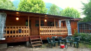 a log cabin with chairs in front of it at VAKANTIEHUIS CASASinPORLEZZA - Camping Italië in Porlezza