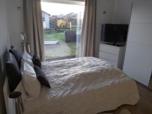 Schlafzimmer mit einem Bett, einem TV und einem Fenster in der Unterkunft Ferienwohnung Auszeit Im Haag in Losheim