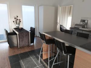eine Küche mit einer schwarzen Theke und schwarzen Stühlen in der Unterkunft Ferienwohnung Auszeit Im Haag in Losheim
