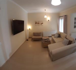a living room with couches and a flat screen tv at Green View Apartment in Áyios Pétros