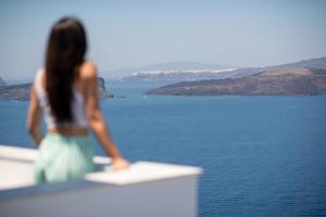 una mujer de pie en una cornisa mirando el agua en Blu Rooms, en Akrotiri