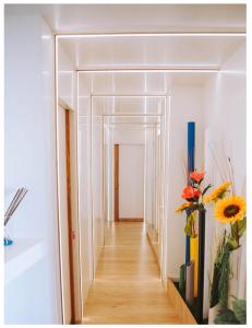 a hallway with white walls and wooden floors and flowers at Avezzano 3e60 in Avezzano