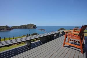 een terras met twee stoelen en uitzicht op het water bij Pacific Rendezvous Resort in Tutukaka