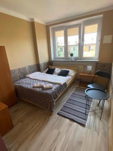 a bedroom with a bed and a table and two windows at Luna Noclegi i Zakwaterowanie in Jarosław