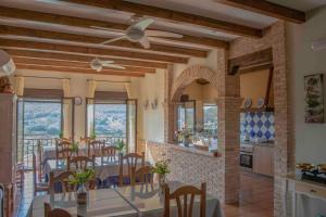 un comedor con mesas, sillas y ventanas en Casa Rural Fuente El Boticario en Aldeanueva de la Vera