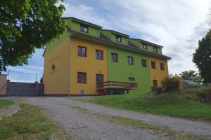 un gran edificio amarillo y verde en una colina en Penzion Bořikovský Dvůr, en Litovany