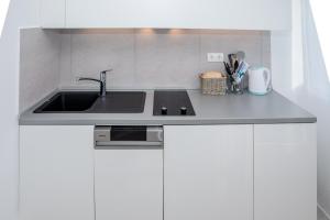 a kitchen with a sink and white cabinets at Sunny Apartments Rab in Rab