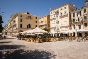 um pátio com mesas, cadeiras e guarda-sóis em Piccolo Lusso Mini Suite em Corfu Town