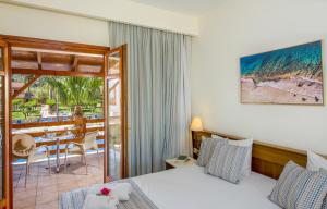 a hotel room with a bed and a balcony with a table at Omega Platanias in Platanias