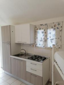 a kitchen with white cabinets and a stove top oven at Campeggio Lao in Scalea