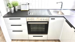 a white kitchen with a stove and sink at Fördekoje in Laboe