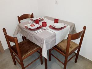 una mesa con mantel blanco y tazas y platos rojos en Adriatic Sunset House, en Petrovac na Moru