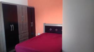 1 dormitorio con 1 cama con colcha roja en Edifício Santorini en Mongaguá