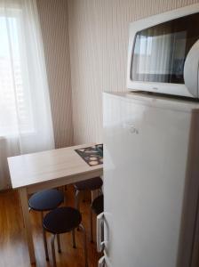 a kitchen with a refrigerator and a table with stools at Apartmenti Saules stūris in Ventspils