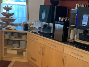 eine Küche mit einer Theke mit einer Mikrowelle und einer Kaffeemaschine in der Unterkunft Hotel Schneeberger in Niederau