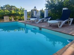 una piscina con 2 sillas y una piscina en Alojamientos Cabezo del Gato, en Aracena